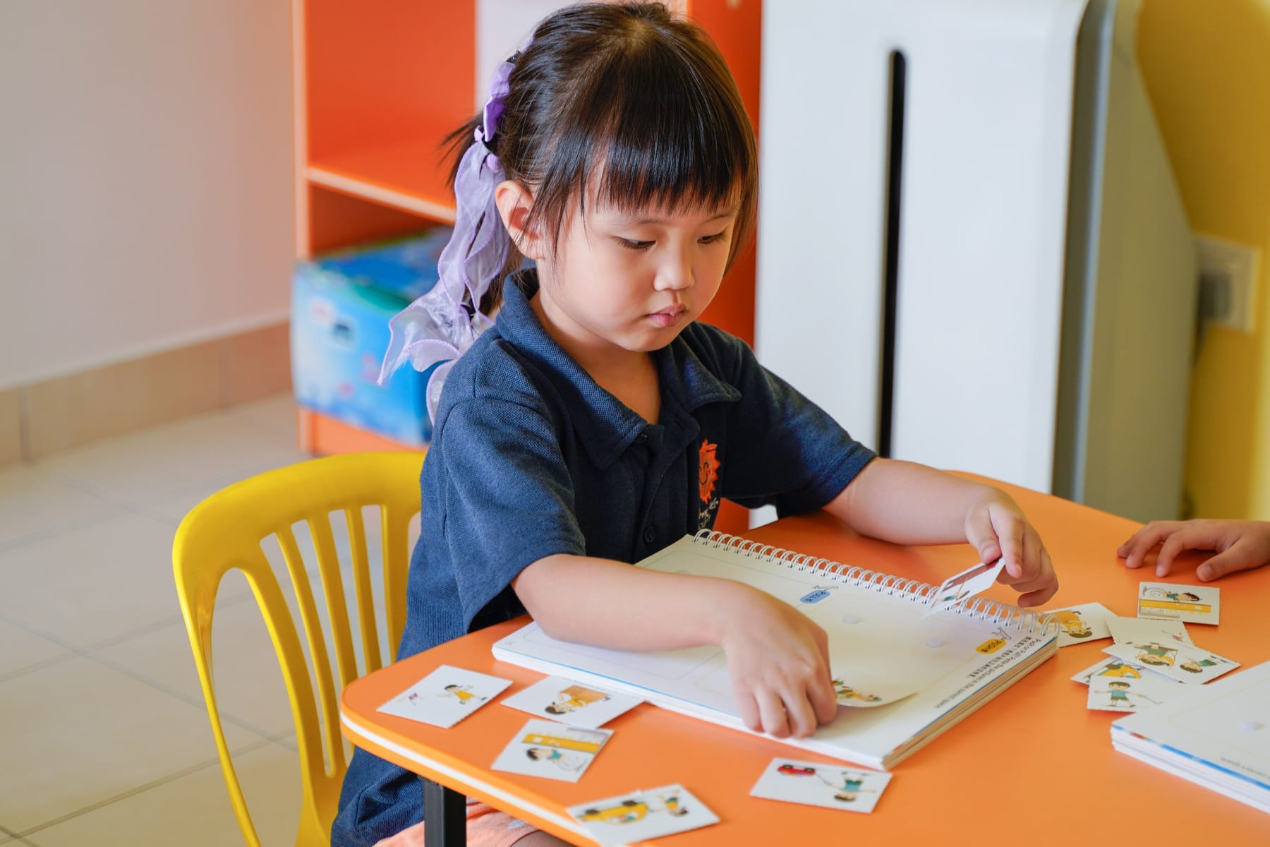 A kindergarten girl matching picture cards in her workbook